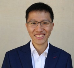 Portrait of Gwee Yi Jie in navy blazer and white shirt, smiling in front of plain background.
